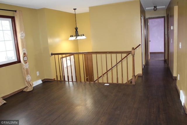 corridor featuring a chandelier and dark wood-type flooring