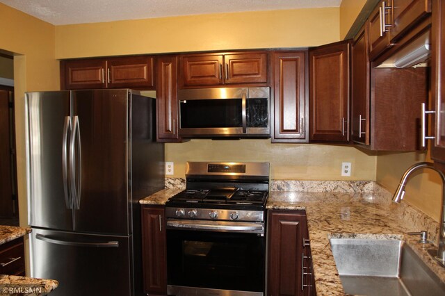 kitchen featuring sink, light stone countertops, and stainless steel appliances