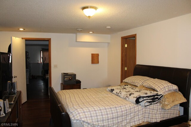 bedroom with a textured ceiling and dark wood-type flooring