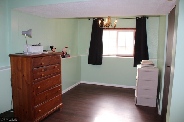 bedroom with a textured ceiling, an inviting chandelier, and dark wood-type flooring