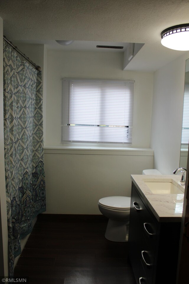 bathroom featuring toilet, vanity, a textured ceiling, and hardwood / wood-style flooring