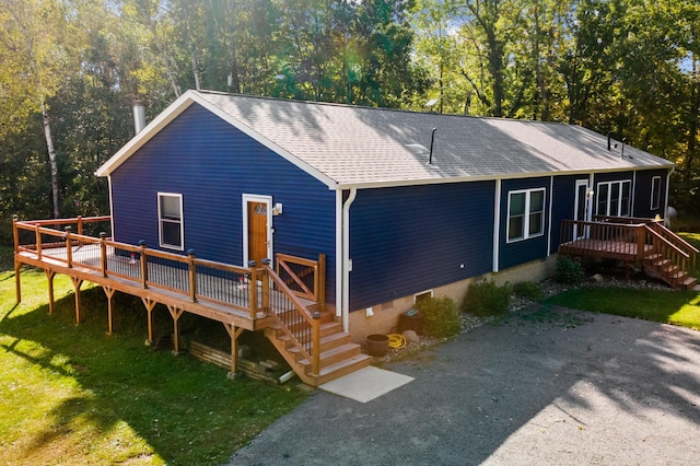 rear view of house featuring a wooden deck and a yard