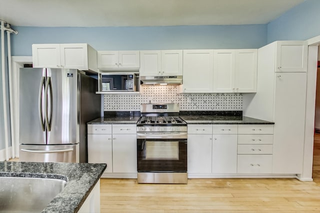 kitchen with dark stone countertops, stainless steel appliances, light hardwood / wood-style floors, and white cabinetry