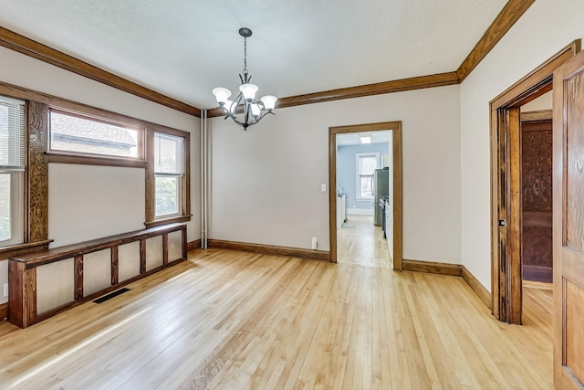 unfurnished room featuring light wood-type flooring, a textured ceiling, ornamental molding, and a chandelier