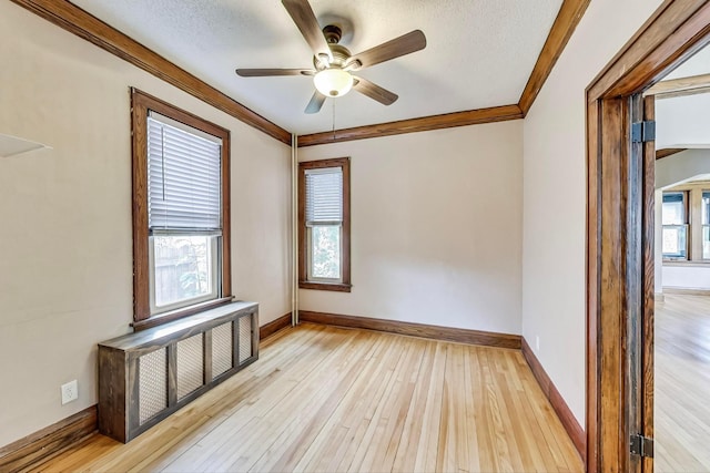 spare room with ceiling fan, a textured ceiling, light hardwood / wood-style floors, and a wealth of natural light