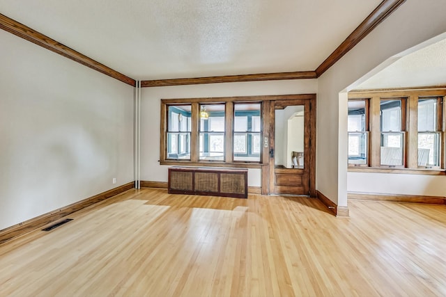 entryway featuring a textured ceiling, crown molding, light hardwood / wood-style floors, and radiator heating unit