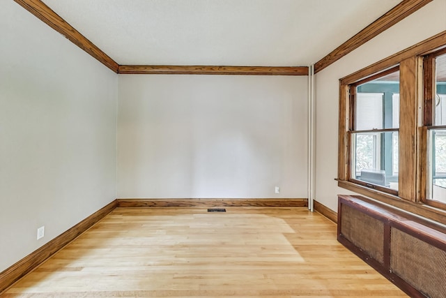 empty room featuring light hardwood / wood-style flooring and crown molding