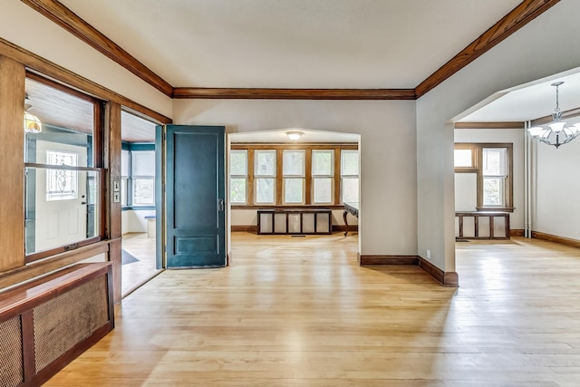 empty room with ornamental molding, an inviting chandelier, and light hardwood / wood-style floors