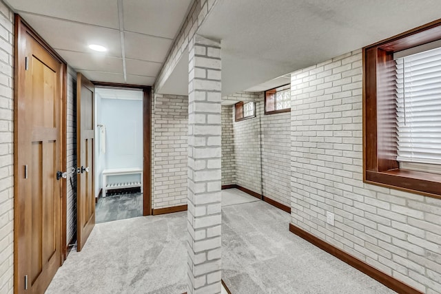 basement with light carpet, brick wall, and a wealth of natural light