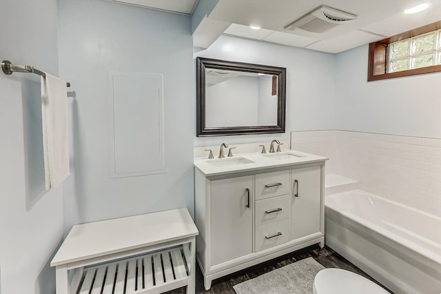 bathroom featuring vanity, a tub to relax in, toilet, and hardwood / wood-style flooring