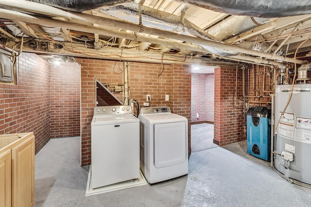 interior space featuring washer and clothes dryer, gas water heater, and brick wall