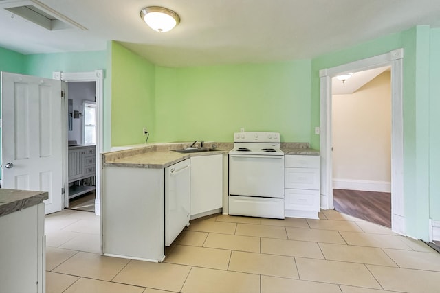 kitchen with light tile patterned floors, white cabinets, sink, and white appliances