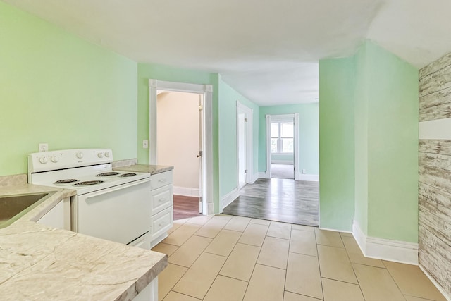 kitchen with light wood-type flooring, white cabinetry, and electric range