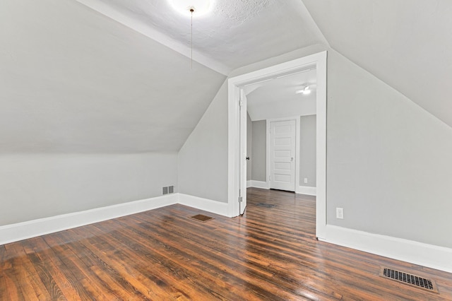 additional living space with vaulted ceiling and dark hardwood / wood-style flooring