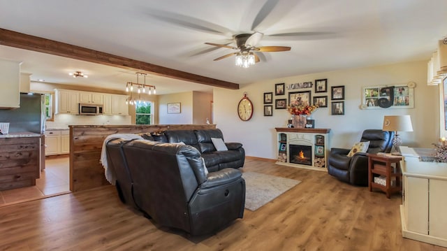 living room with ceiling fan, beamed ceiling, and light hardwood / wood-style floors