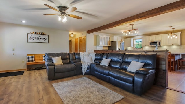 living room with ceiling fan with notable chandelier, beam ceiling, and wood-type flooring