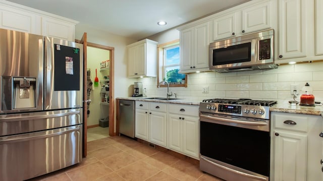 kitchen featuring light tile patterned floors, stainless steel appliances, light stone countertops, white cabinets, and sink