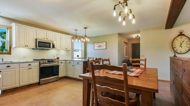 kitchen with a wealth of natural light, stainless steel appliances, pendant lighting, and white cabinetry