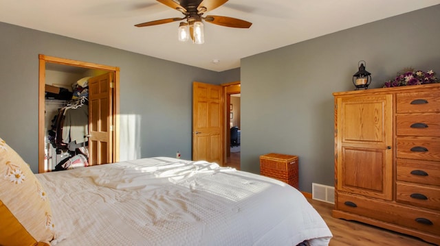 bedroom with ceiling fan, a closet, a spacious closet, and light wood-type flooring