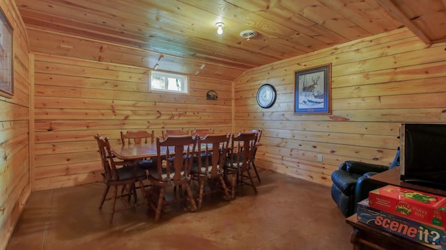 dining space with wood ceiling, lofted ceiling, concrete flooring, and wood walls