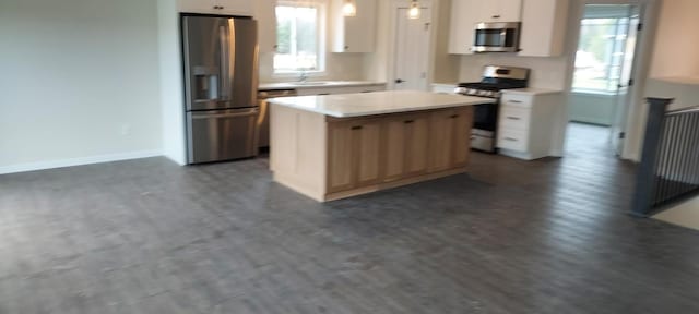 kitchen with a center island, hanging light fixtures, white cabinetry, light countertops, and appliances with stainless steel finishes