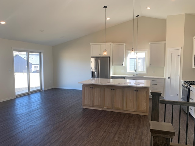 kitchen with sink, dark wood-type flooring, appliances with stainless steel finishes, white cabinetry, and a kitchen island