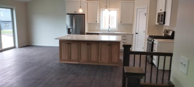 kitchen featuring white cabinetry, stainless steel appliances, decorative light fixtures, and a kitchen island