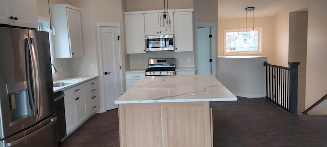 kitchen with white cabinetry, light stone counters, decorative light fixtures, a kitchen island, and stainless steel appliances