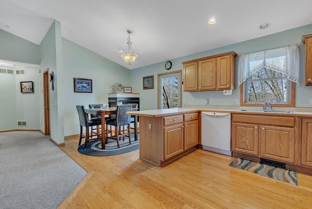 kitchen with vaulted ceiling, dishwasher, pendant lighting, kitchen peninsula, and sink