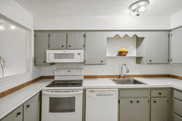 kitchen with white appliances, light countertops, a sink, and gray cabinetry