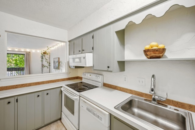 kitchen with a textured ceiling, white appliances, a sink, light countertops, and gray cabinets