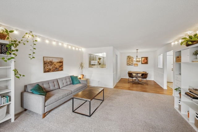 living room featuring light carpet, light wood finished floors, and a textured ceiling