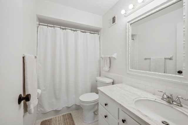 bathroom featuring visible vents, toilet, a wainscoted wall, vanity, and tile walls