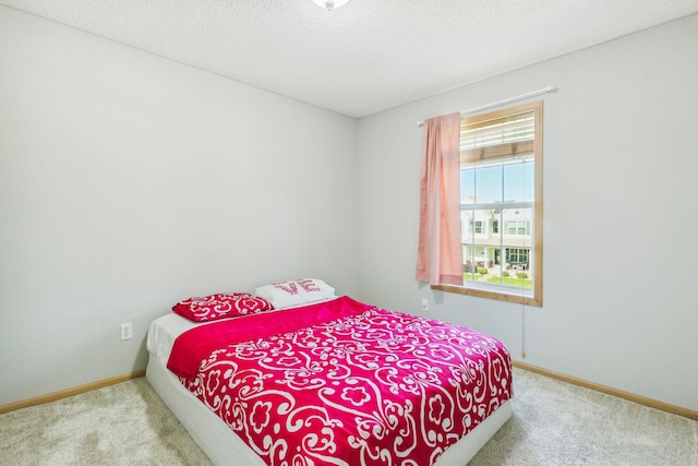 bedroom featuring light carpet and a textured ceiling