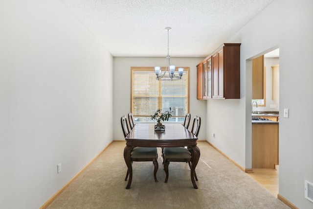 carpeted dining area featuring sink, a textured ceiling, and a notable chandelier