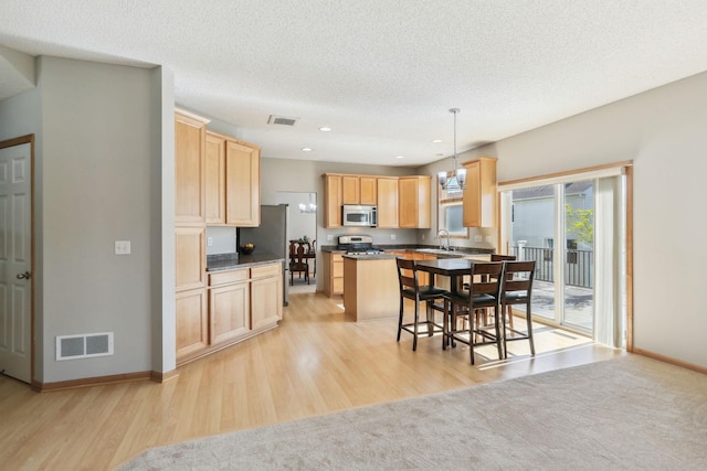 kitchen featuring sink, hanging light fixtures, a kitchen island, stainless steel appliances, and a kitchen bar