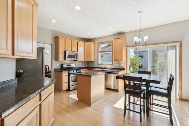 kitchen with sink, decorative light fixtures, light brown cabinets, a kitchen island, and stainless steel appliances