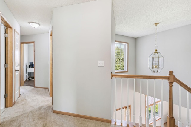 corridor with light carpet and a textured ceiling