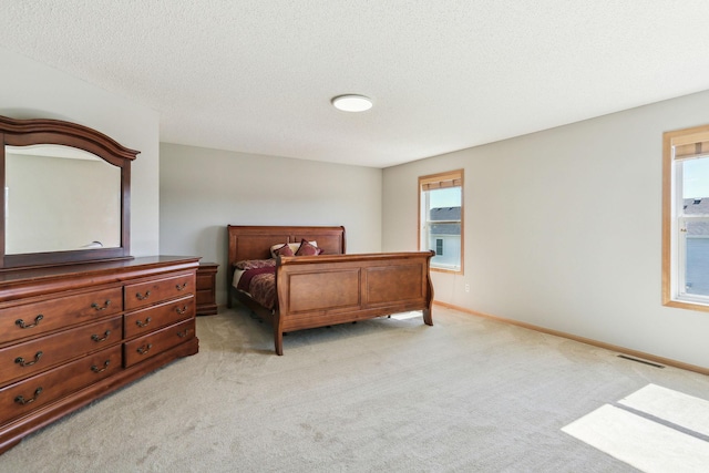 bedroom with light colored carpet and a textured ceiling