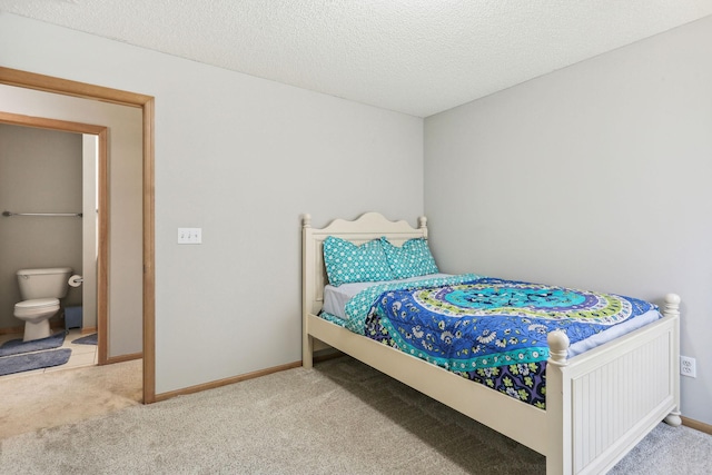 carpeted bedroom featuring connected bathroom and a textured ceiling