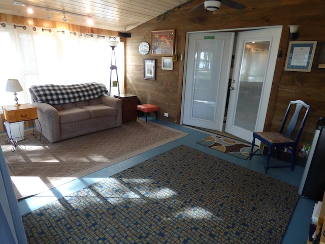 living room with ceiling fan, wood ceiling, wood walls, and vaulted ceiling