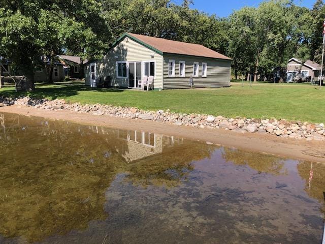 back of property featuring a lawn and a water view