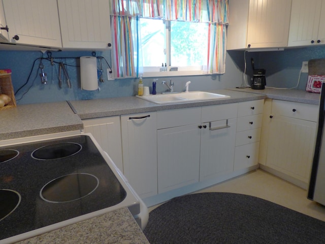 kitchen featuring white cabinets, sink, and range