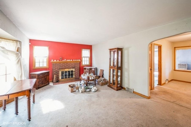 living area featuring light colored carpet, a healthy amount of sunlight, and a fireplace