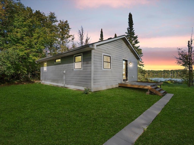 property exterior at dusk featuring a lawn