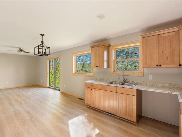 kitchen with a sink, light wood-type flooring, baseboards, ceiling fan, and light brown cabinets