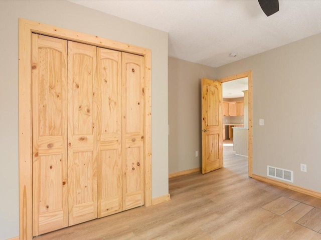 unfurnished bedroom with baseboards, a ceiling fan, light wood finished floors, and visible vents