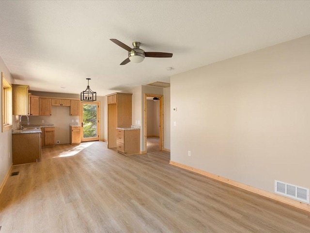 unfurnished living room with sink, light hardwood / wood-style flooring, and ceiling fan