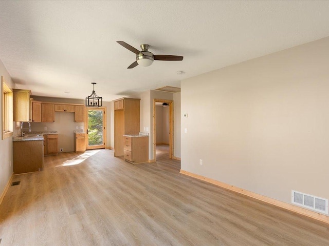 unfurnished living room with visible vents, light wood finished floors, baseboards, and a ceiling fan