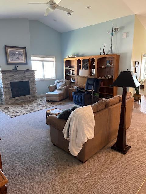 carpeted living room featuring ceiling fan, a fireplace, and vaulted ceiling